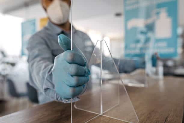 Man fixing plexiglass at an office counter